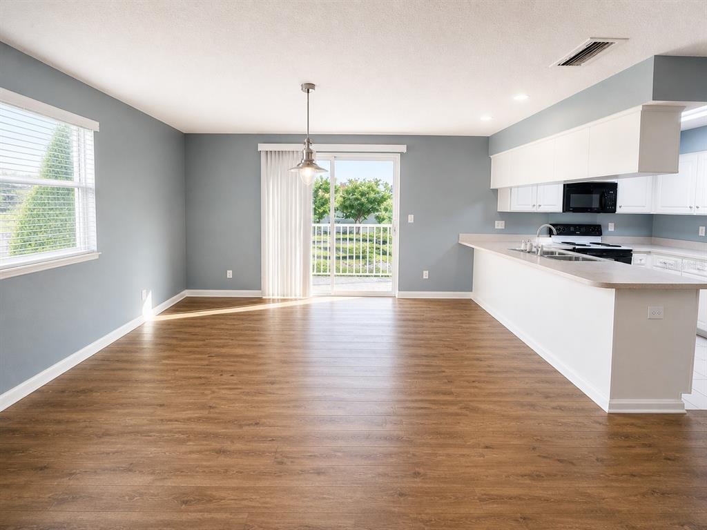 An open-concept dining area features wood-look flooring, blue walls, and a sliding glass door — 1013 APOLLO BEACH BOULEVARD UNIT 202, APOLLO BEACH, FL