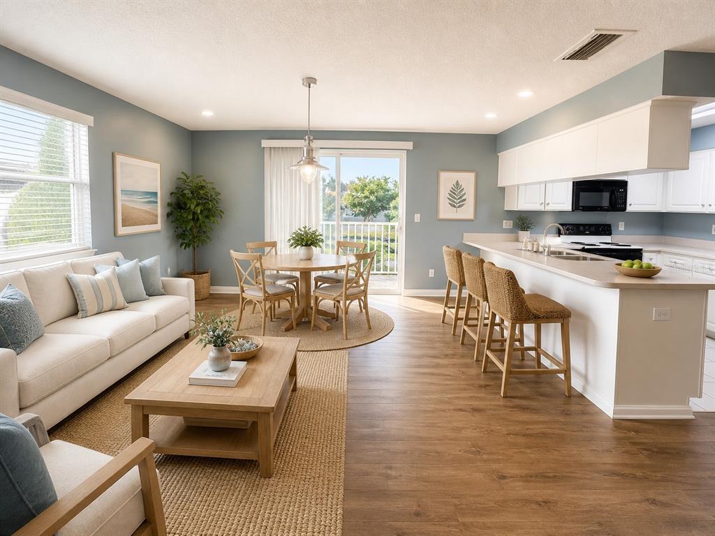 An open-concept living and dining area features light blue walls, wood flooring, and a kitchen island — 1013 APOLLO BEACH BOULEVARD UNIT 202, APOLLO BEACH, FL