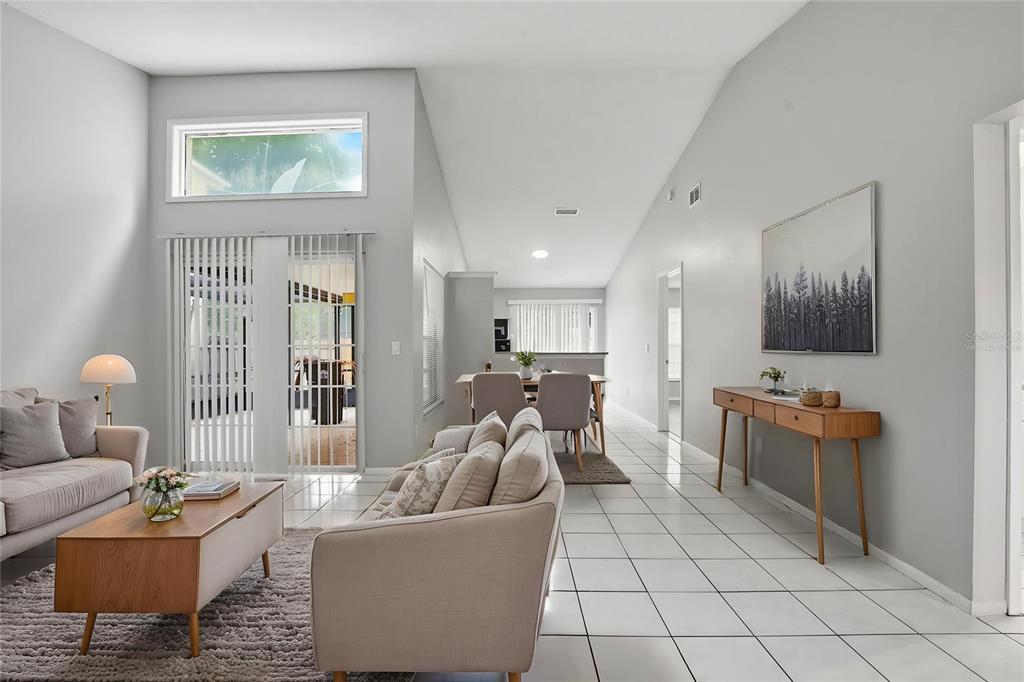 A living and dining area features white tile floors, vaulted ceilings, and neutral-toned furniture — 1183 PIN OAK DRIVE, APOPKA, FL