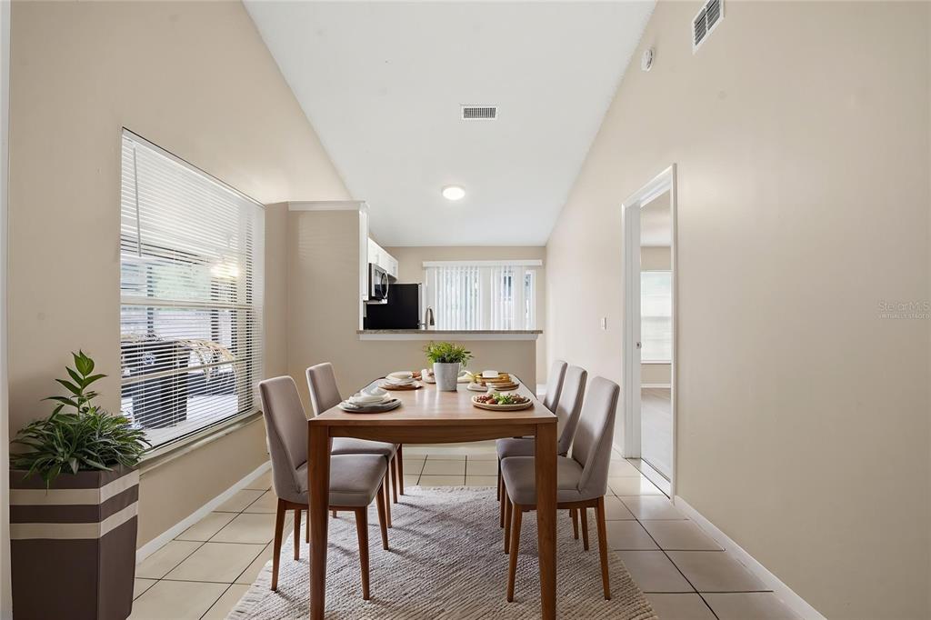 A dining area with a wooden table, chairs, tile flooring, and a view of the kitchen — 1183 PIN OAK DRIVE, APOPKA, FL