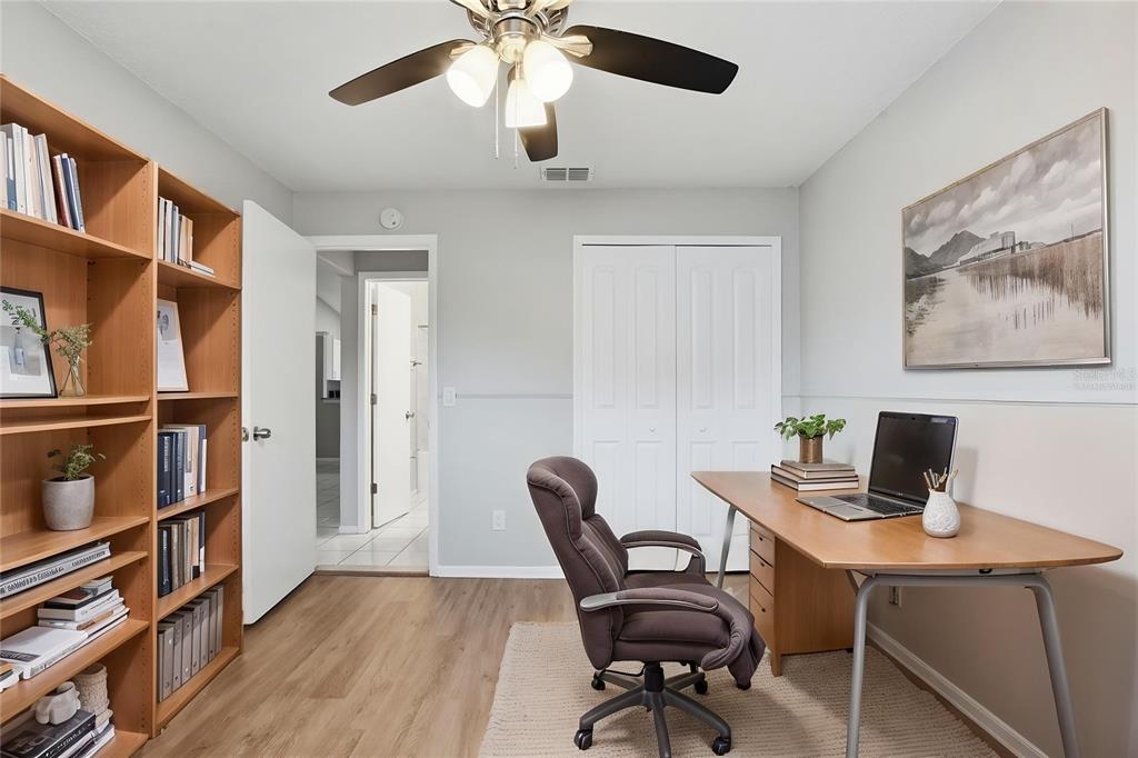 A home office features wood flooring, a wooden bookshelf, a desk with a chair, and closets — 1183 PIN OAK DRIVE, APOPKA, FL