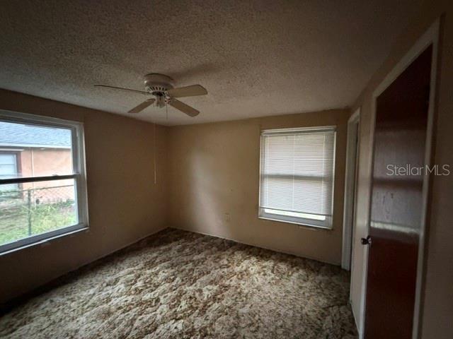 A bedroom with beige walls, a ceiling fan, patterned carpet, and two windows with blinds — 1050 BEACH LANE, WINTER HAVEN, FL