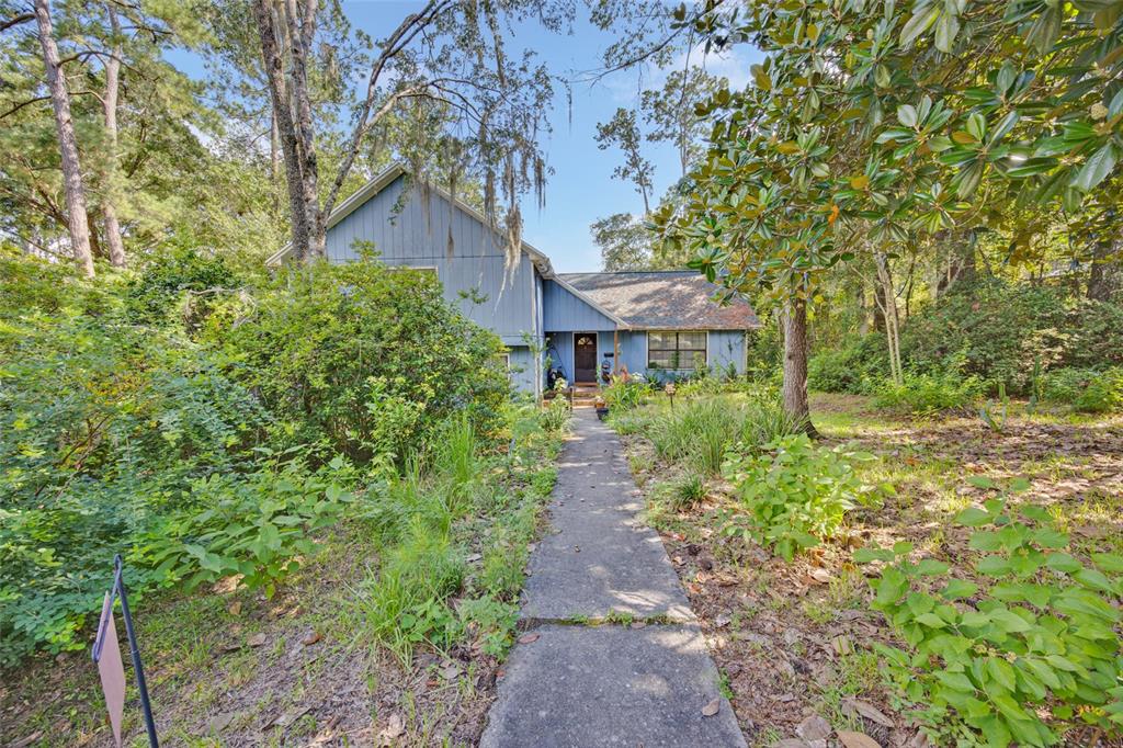 A blue two-story house with a concrete walkway leading to the front entrance — 7607 NW 42ND AVENUE, GAINESVILLE, FL