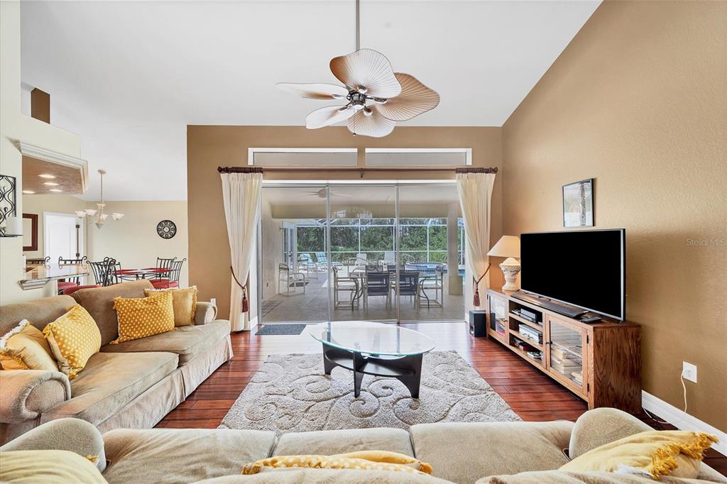 A living room features a ceiling fan, a television on a wooden console, and sliding doors — 36 PINE VALLEY COURT, ROTONDA WEST, FL