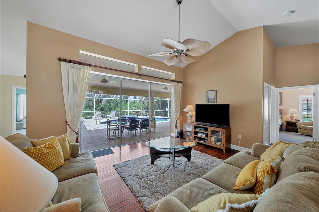 A living room with hardwood floors, a ceiling fan, and sliding doors leading to a pool — 36 PINE VALLEY COURT, ROTONDA WEST, FL
