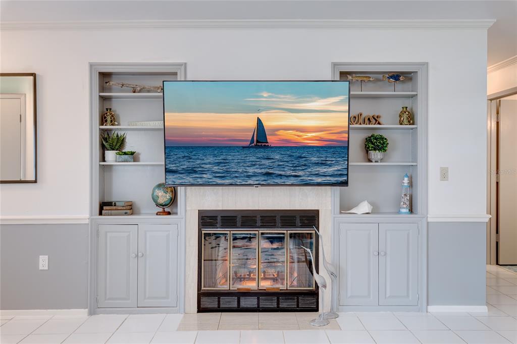 A living room features a fireplace with a mounted television flanked by built-in gray shelving — 231 CADDY ROAD, ROTONDA WEST, FL