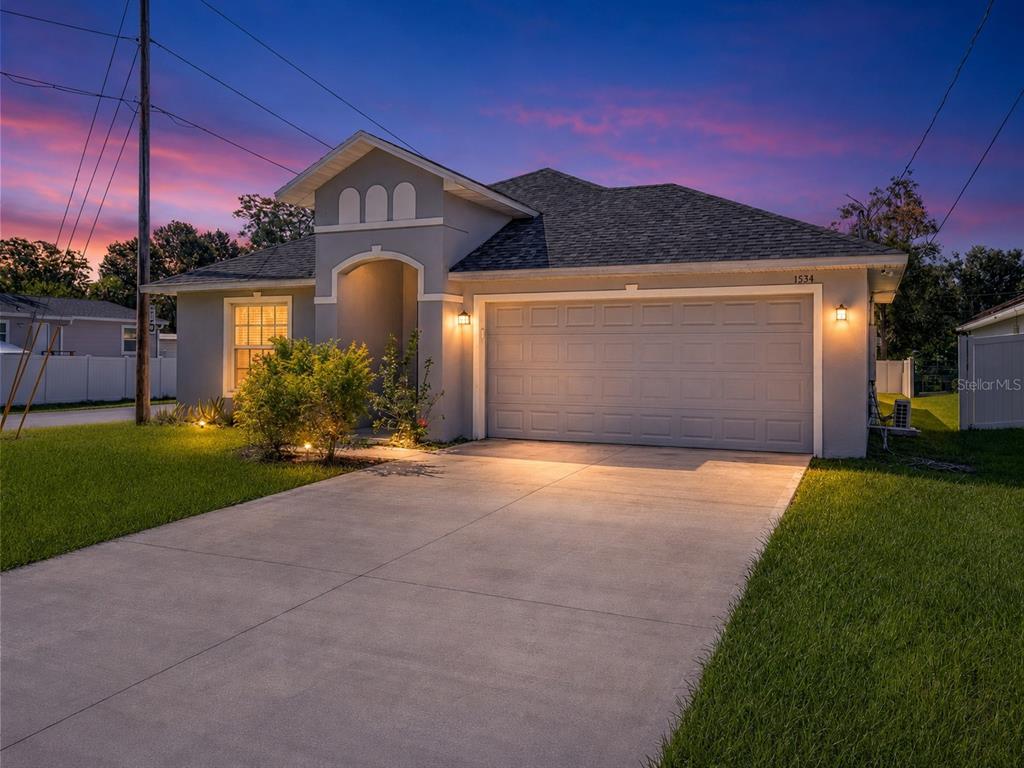 A single-story house with a gray garage, stucco exterior, and a driveway at sunset — 1534 PINE STREET, ORLANDO, FL