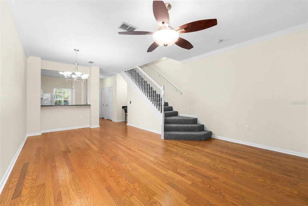 A living area with hardwood floors, a staircase, and a ceiling fan — 5007 NW 45TH ROAD UNIT 103, GAINESVILLE, FL