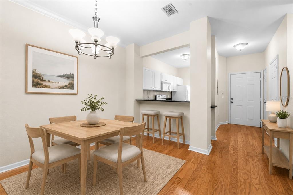 A dining area with a wooden table, four chairs, and a breakfast bar with two stools — 5007 NW 45TH ROAD UNIT 103, GAINESVILLE, FL