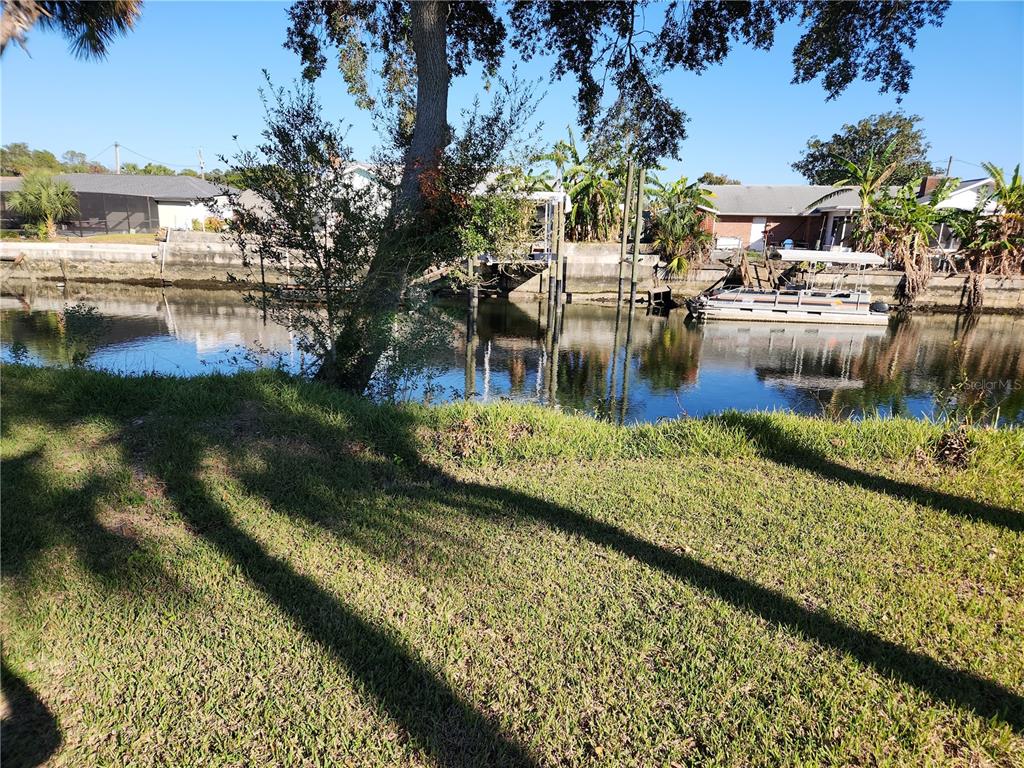 A grassy lawn overlooks a canal with a boat dock and a pontoon boat — 3879 N SEMINOLE POINT, CRYSTAL RIVER, FL