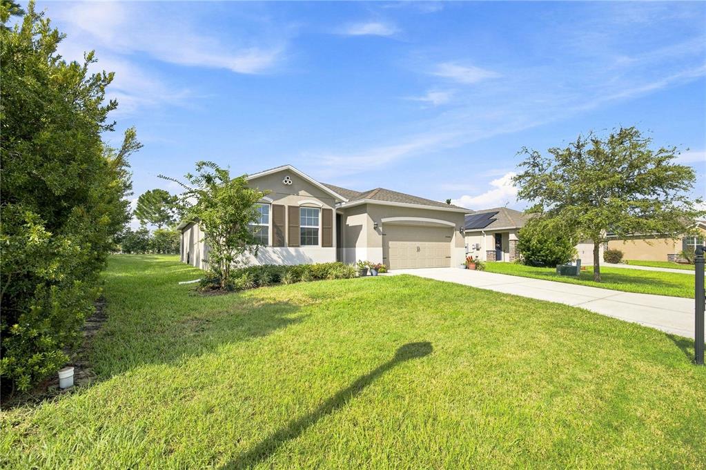 A single-story suburban house with a tan exterior, two-car garage, and a green lawn — 6457 SW 89TH LOOP, OCALA, FL
