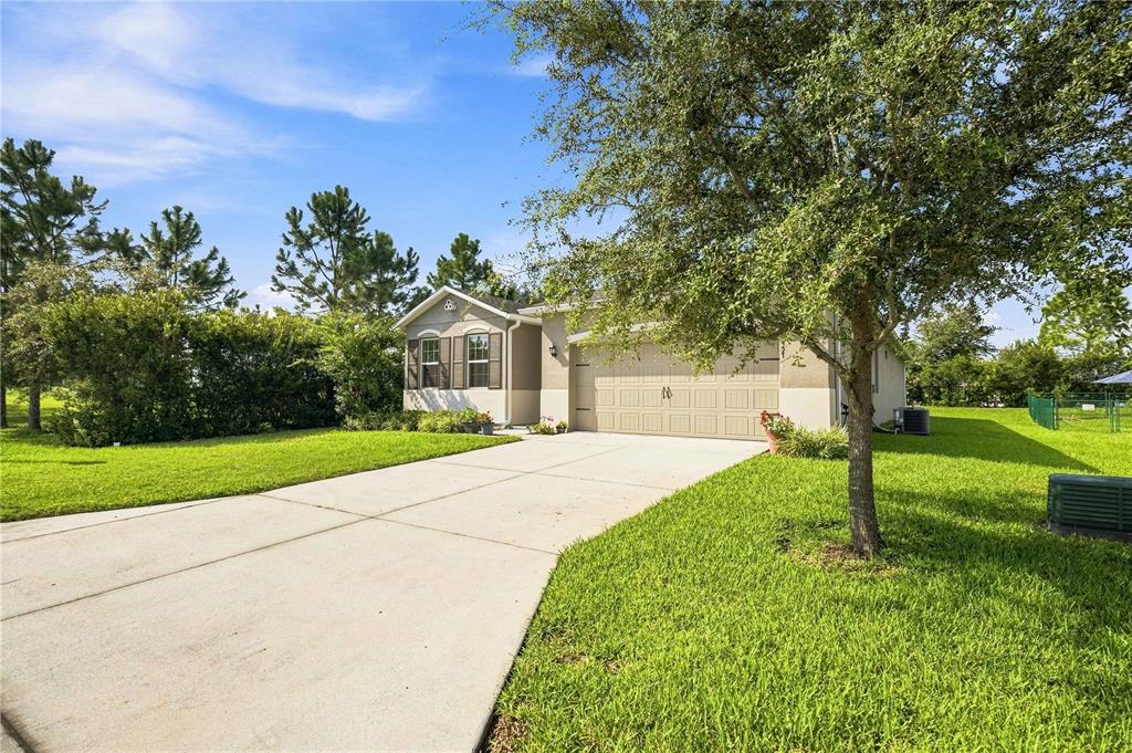 A single-story house with a beige exterior, a two-car garage, and a concrete driveway — 6457 SW 89TH LOOP, OCALA, FL