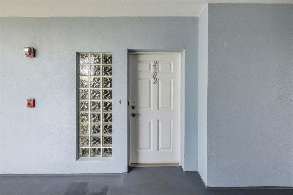 A white front door with the number 2502 sits beside a vertical glass block window — 5300 S ATLANTIC AVENUE UNIT 2-502, NEW SMYRNA BEACH, FL