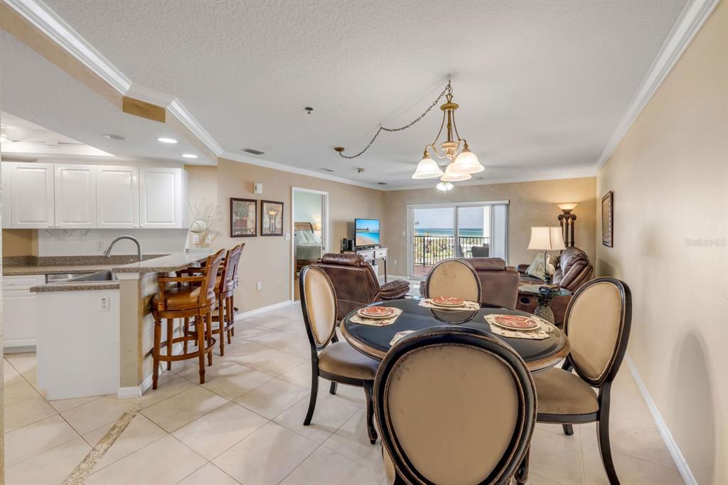 An open-concept living and dining area features a kitchen island, tile flooring, and balcony views — 5300 S ATLANTIC AVENUE UNIT 2-502, NEW SMYRNA BEACH, FL