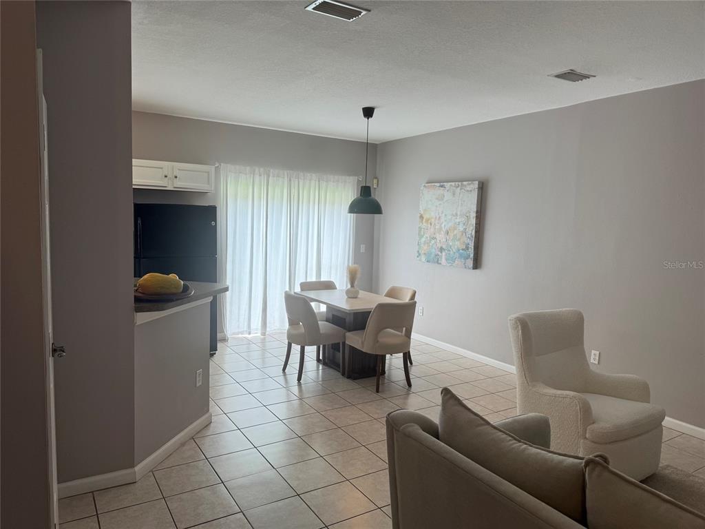 A dining area with a table and chairs sits adjacent to a kitchen and living space — 319 SUMMER CLOUDS PLACE, BRANDON, FL