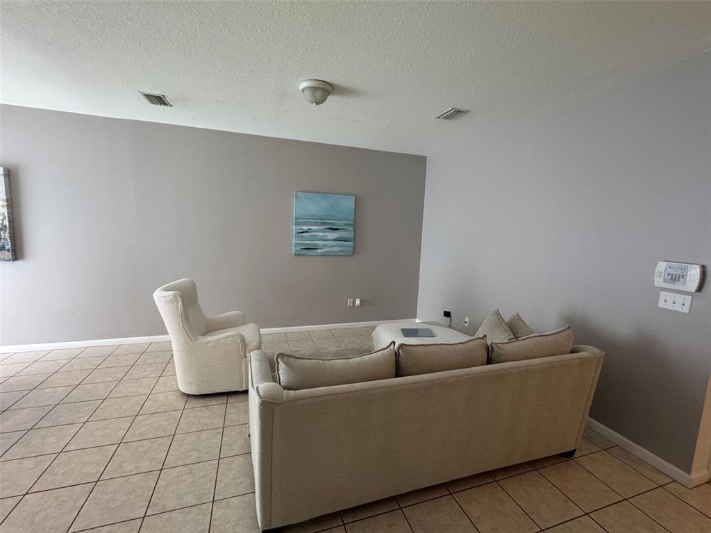 A living room features light-colored tile flooring, gray walls, a sofa, and an armchair — 319 SUMMER CLOUDS PLACE, BRANDON, FL