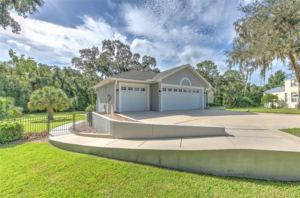 A detached three-car garage with a concrete driveway and a low retaining wall — 5207 MERION RD, VALRICO, FL