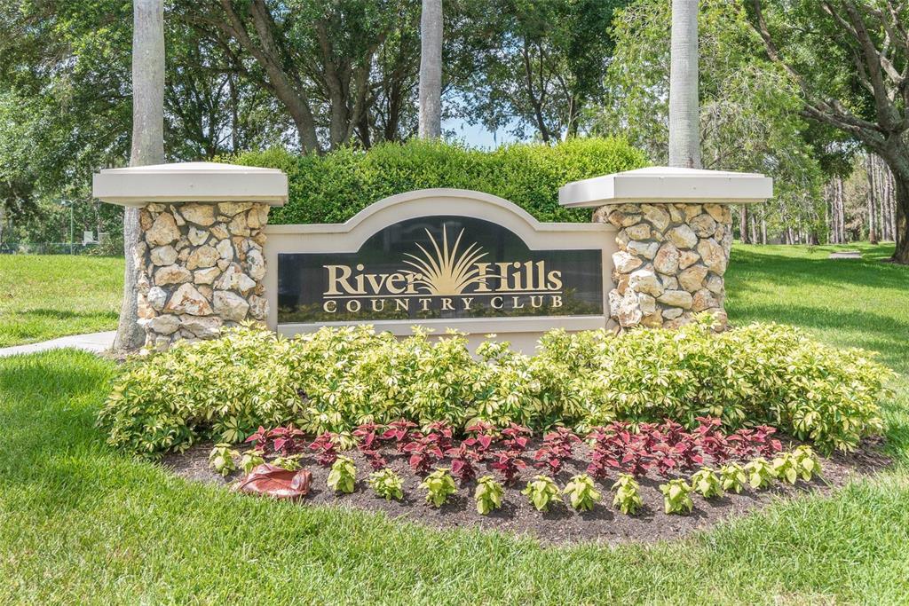A stone monument sign for River Hills Country Club sits in a landscaped garden area — 5207 MERION RD, VALRICO, FL