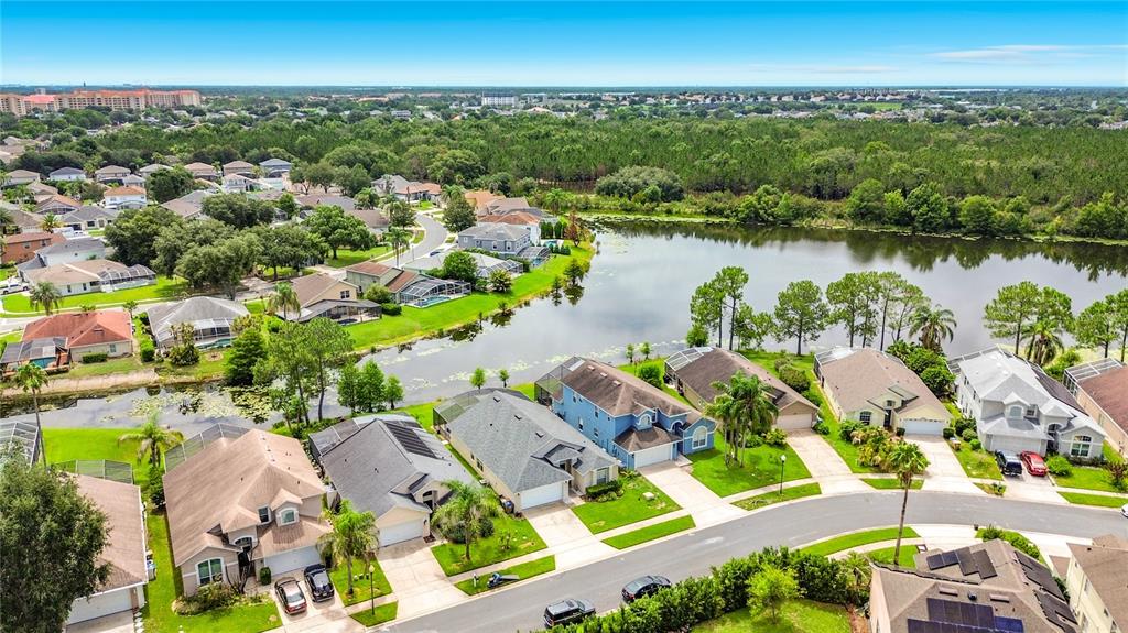 An aerial view shows suburban houses with swimming pools situated along a lake and forest — 2873 BLOOMING ALAMANDA LOOP, KISSIMMEE, FL