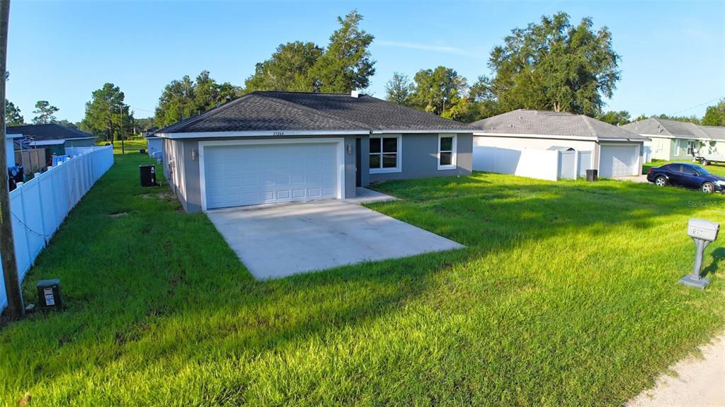 A single-story house with a gray exterior, a two-car garage, and a white vinyl fence — 13264 SW 111TH LANE, DUNNELLON, FL