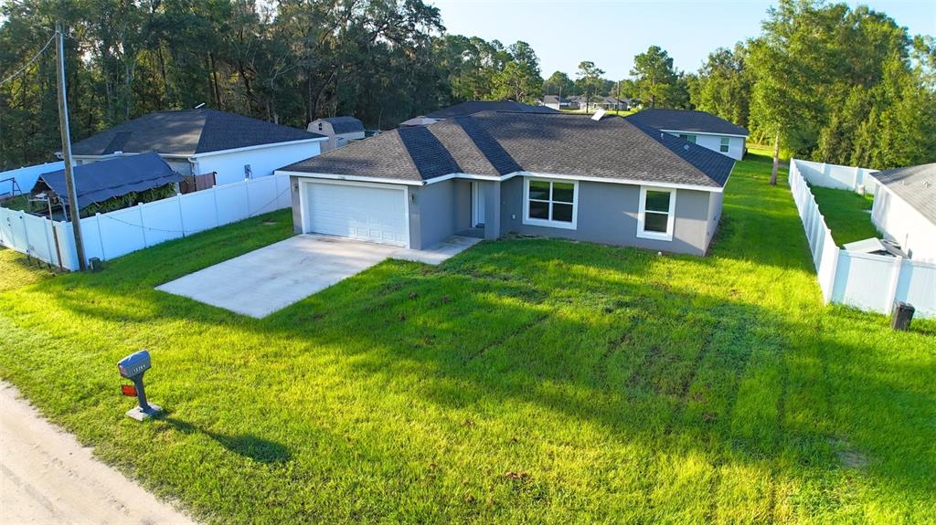 An aerial view of a gray single-story house with a white garage and vinyl fencing — 13264 SW 111TH LANE, DUNNELLON, FL