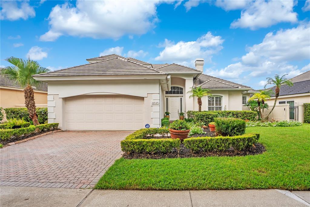 A single-story house with a beige stucco exterior, a two-car garage, and a landscaped yard — 10925 WOODCHASE CIRCLE, ORLANDO, FL
