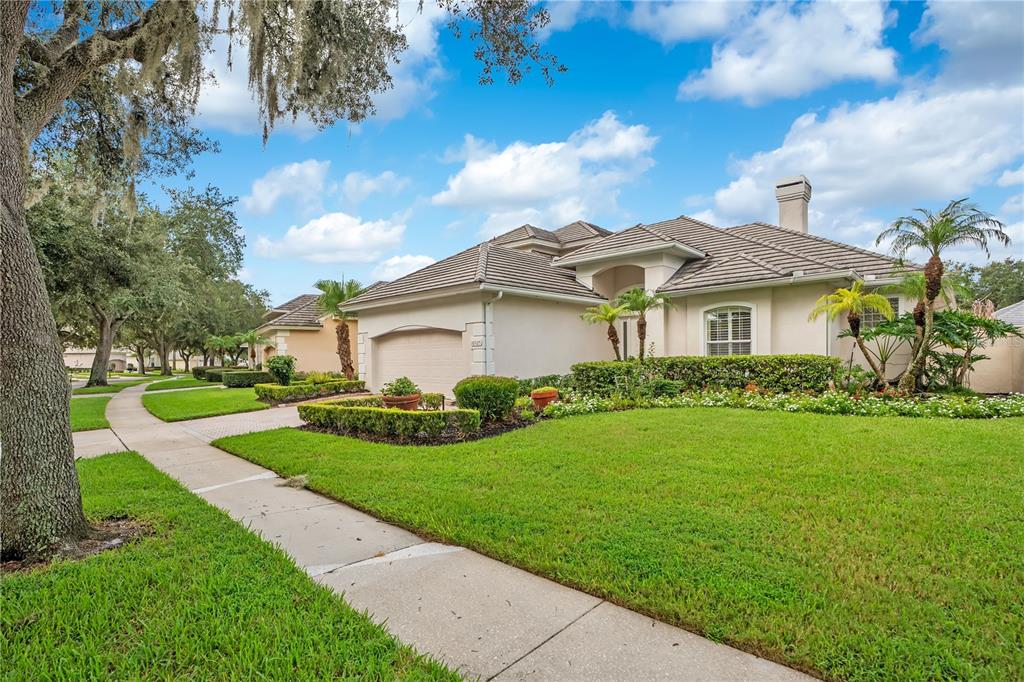 A single-story suburban house with a tan stucco exterior, tile roof, and landscaped front yard — 10925 WOODCHASE CIRCLE, ORLANDO, FL