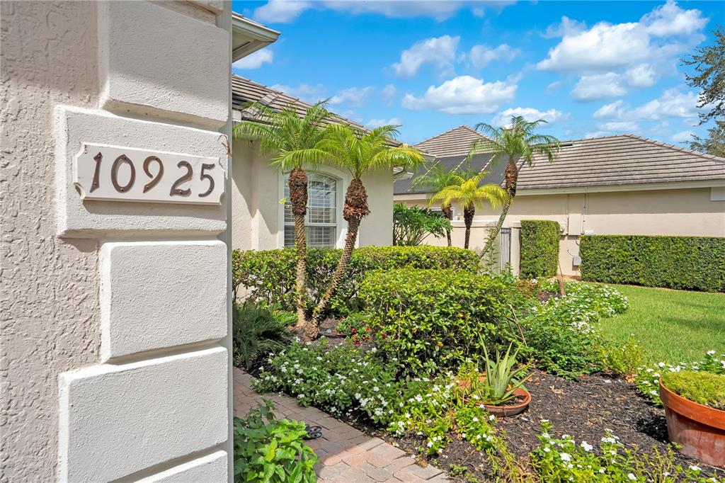 A view of a house exterior featuring a stone address plaque, landscaping, and palm trees — 10925 WOODCHASE CIRCLE, ORLANDO, FL