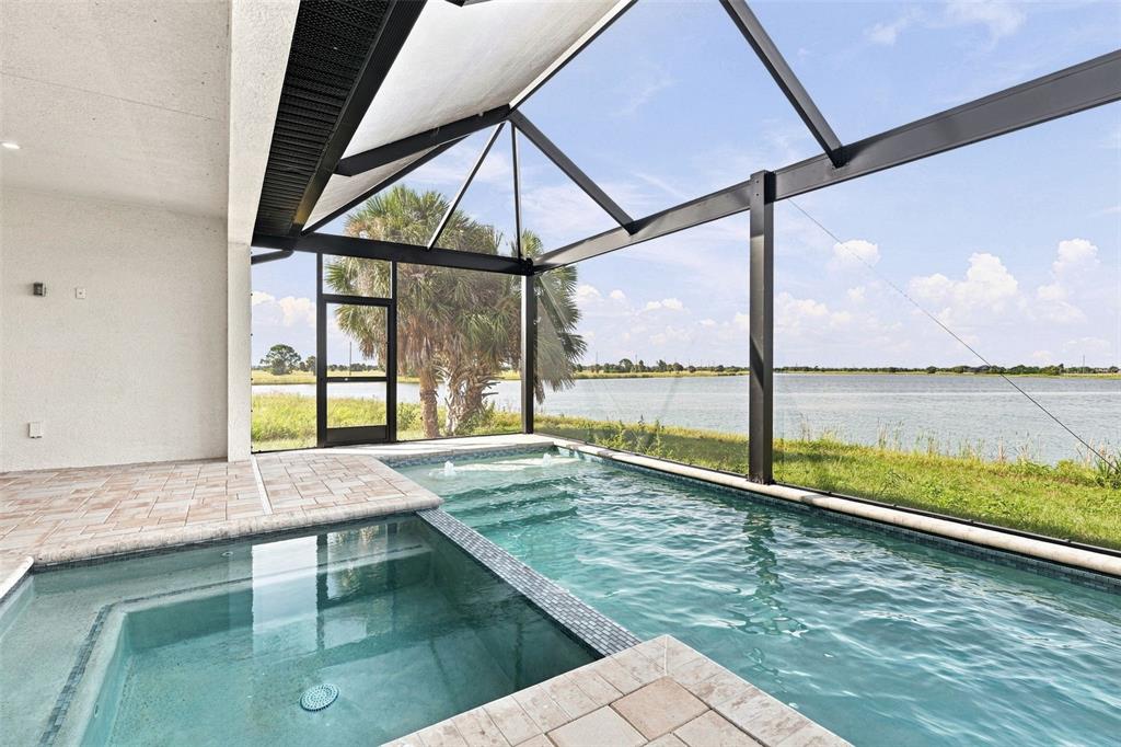 A modern single-story house with a paved driveway, palm trees, and a waterfront view at sunset — 44 SUNFLOWER DRIVE, PLACIDA, FL