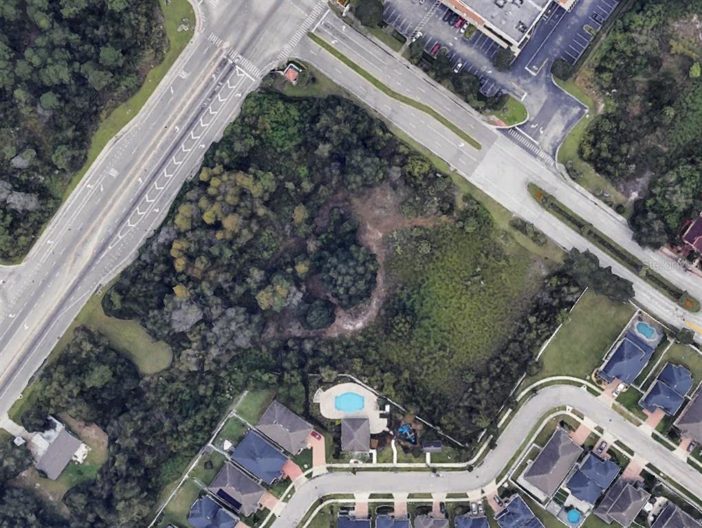 This aerial view shows a vacant, wooded lot bordered by roads and a residential neighborhood — SIMPSON ROAD, KISSIMMEE, FL