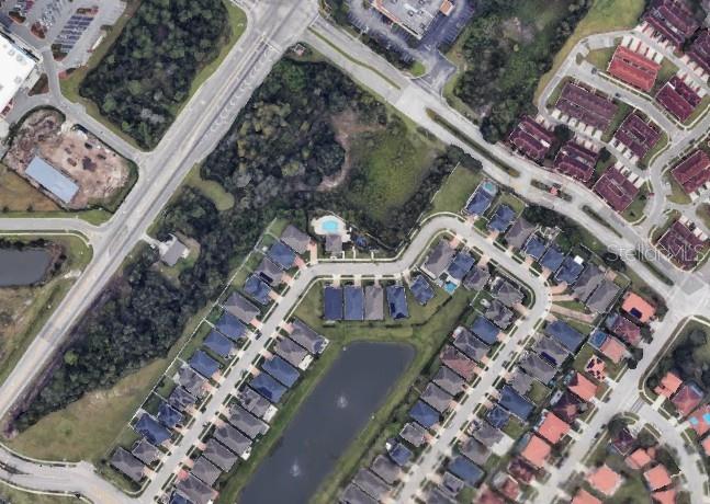This is an aerial view of a residential neighborhood featuring houses, a pond, and roads — SIMPSON ROAD, KISSIMMEE, FL