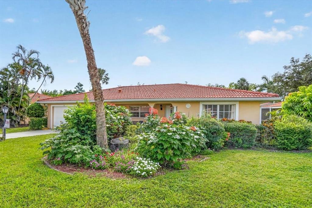 A single-story house with a tiled roof and a landscaped front yard with a palm tree — 122 49TH COURT E, PALMETTO, FL