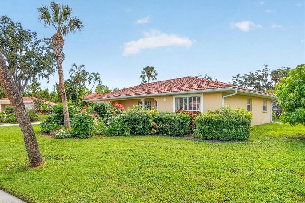 A single-story house with a tiled roof and landscaped yard under a blue sky — 122 49TH COURT E, PALMETTO, FL