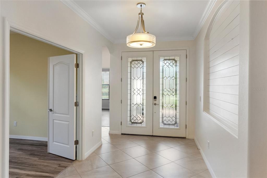 A tiled entryway features a double front door with glass inserts and a hanging light — 9730 CARNOUSTIE PLACE, BRADENTON, FL