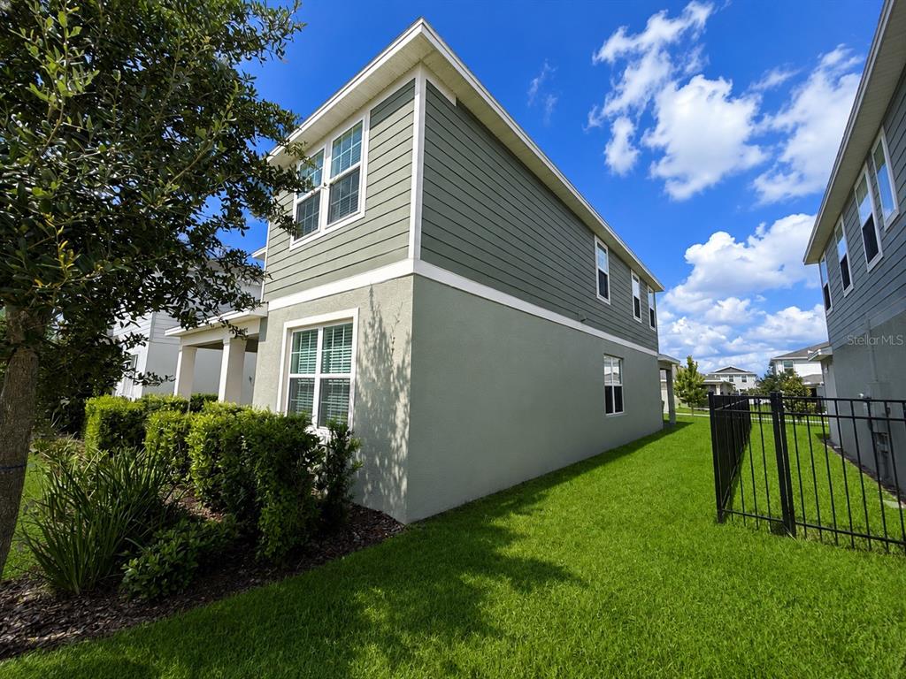 A two-story house with green siding and stucco exterior features a side yard and fence — 4086 LUSH VIEW DRIVE, APOPKA, FL