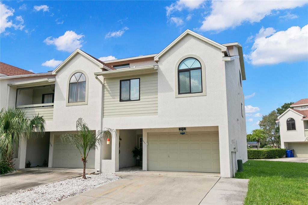 A two-story townhouse with a light-colored stucco exterior, two garages, and arched windows — 2376 HANOVER DRIVE, DUNEDIN, FL