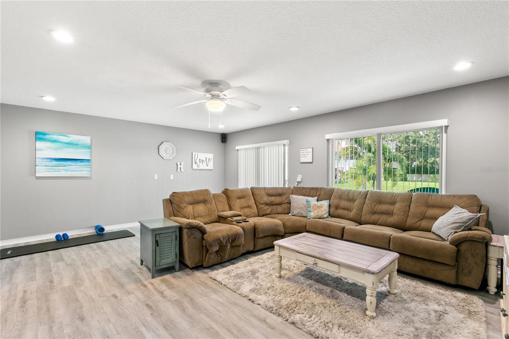 A living room features a large brown sectional sofa, a coffee table, and light flooring — 2376 HANOVER DRIVE, DUNEDIN, FL