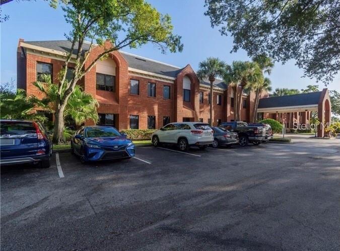A multi-story brick office building features a covered entrance and a paved parking lot — 2500 W LAKE MARY BOULEVARD UNIT 107 D, LAKE MARY, FL