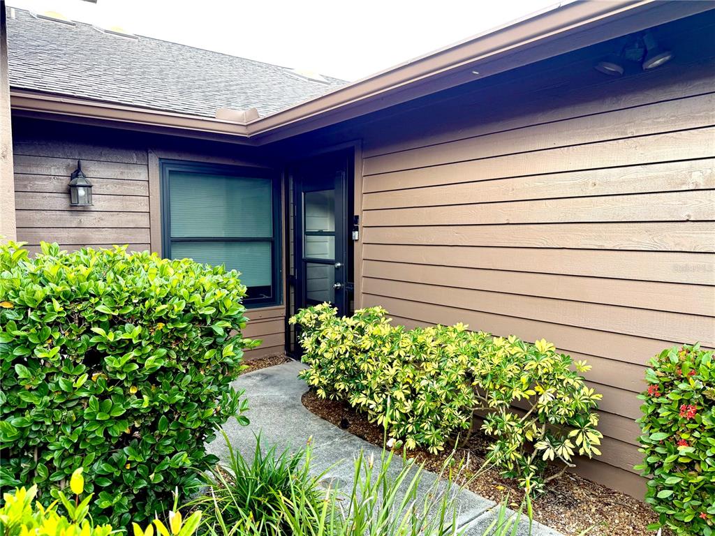 A concrete walkway leads to the front entrance of a house with brown horizontal siding — 5813 MERION WAY UNIT 5813, SARASOTA, FL