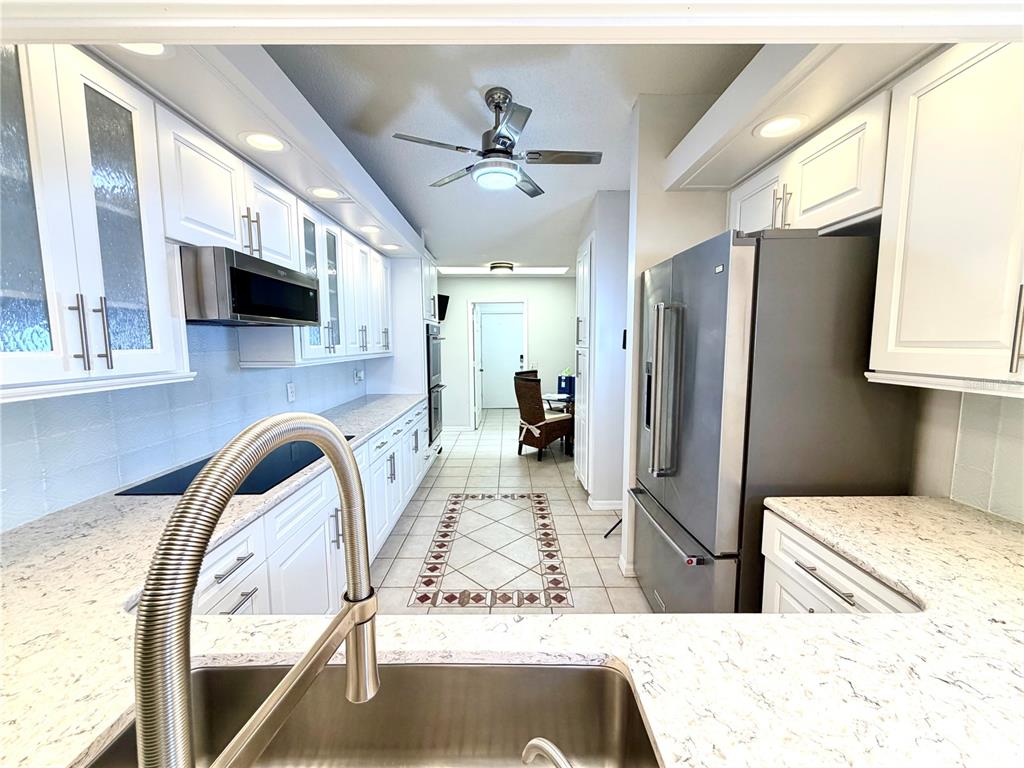 A galley kitchen features white cabinets, stainless steel appliances, and light-colored granite countertops — 5813 MERION WAY UNIT 5813, SARASOTA, FL