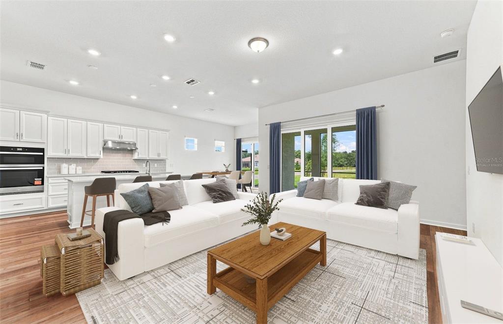 A modern open-concept kitchen with a granite island overlooks a living area with blue paneling — 9452 DAYLIGHT DRIVE, PARRISH, FL