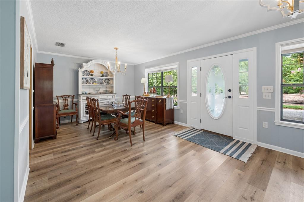 A dining room with light blue walls, wood-look flooring, a white hutch, and a front door — 10283 RIVER WOOD DRIVE, LIVE OAK, FL