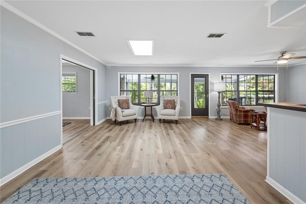 A living room with light wood floors, two armchairs, a skylight, and a glass door — 10283 RIVER WOOD DRIVE, LIVE OAK, FL