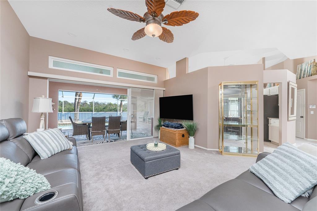 A living room with gray furniture, carpet, tile flooring, and a glass display cabinet — 310 CORAL CREEK DRIVE, PLACIDA, FL
