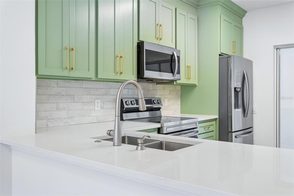 A kitchen features light green cabinets, stainless steel appliances, and white countertops with a sink — 279 COUNTRYSIDE KEY BOULEVARD, OLDSMAR, FL