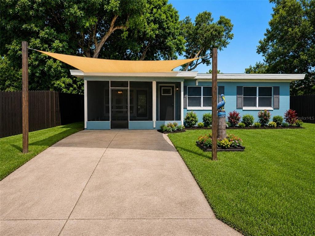 A blue single-story house features a screened-in porch, a concrete driveway, and a shade sail — 3113 25TH STREET N, ST PETERSBURG, FL