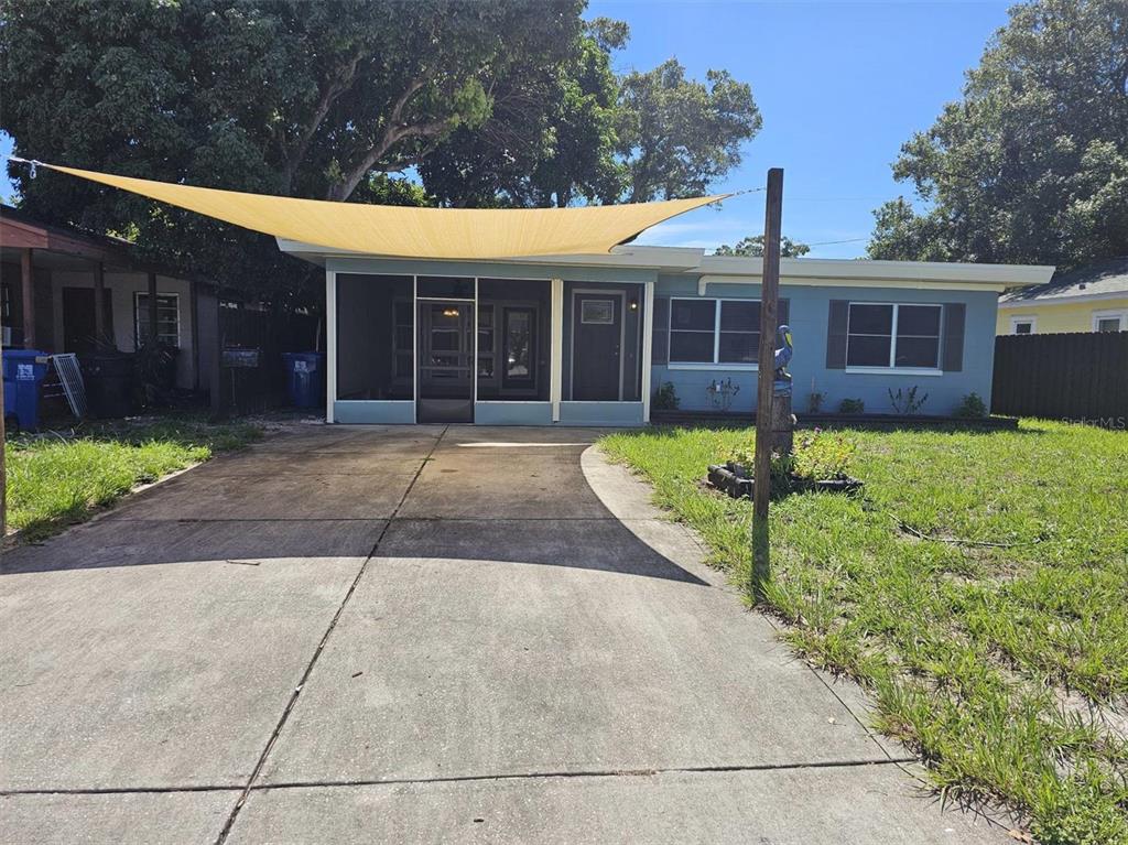 A blue single-story house features a screened-in porch and a large tan shade sail overhead — 3113 25TH STREET N, ST PETERSBURG, FL