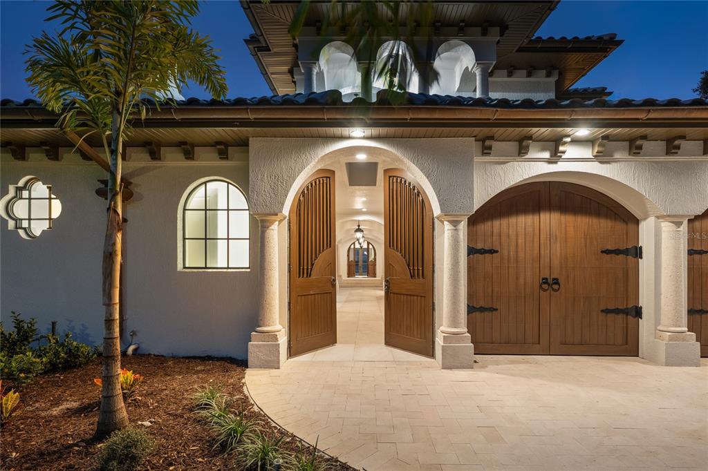 A Mediterranean-style home exterior features a stone-paved courtyard, arched wooden doors, and a palm tree — 800 W 2ND AVENUE, WINDERMERE, FL