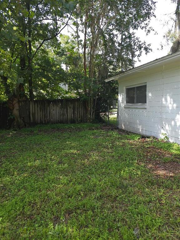 A white house exterior sits next to a wooden fence in a grassy backyard — 3501 NW 17 TERRACE, GAINESVILLE, FL