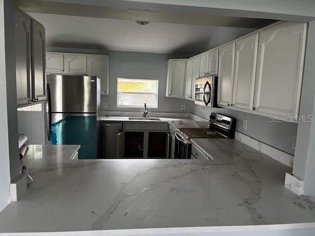 A kitchen features white cabinets, stainless steel appliances, and a white marble-patterned countertop peninsula — 1702 N GORDON STREET, PLANT CITY, FL